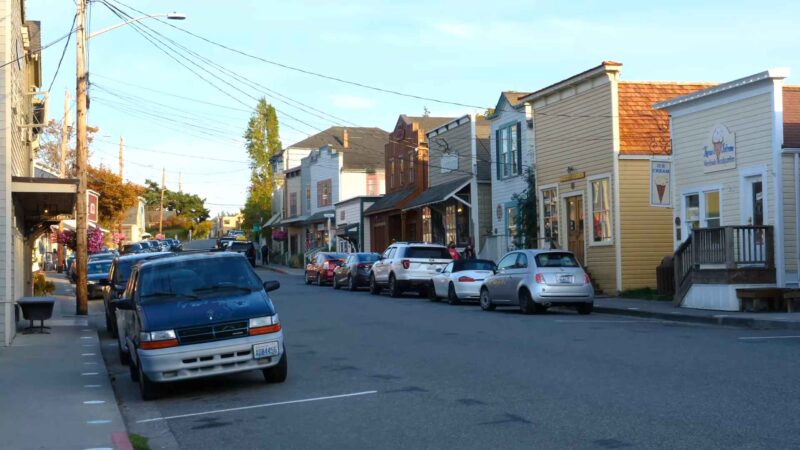 Street view of downtown Coupeville with parked cars, historic wooden buildings, and small shops