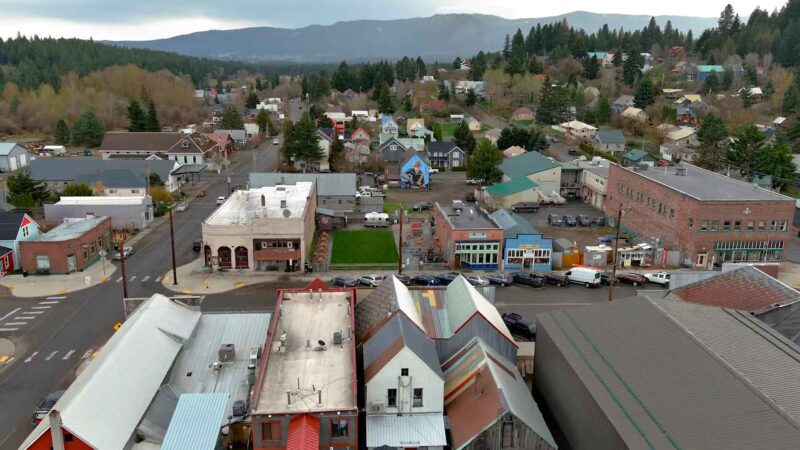 Aerial view of downtown Roslyn, Washington, showing colorful historic buildings, tree-lined streets, and mountains in the background