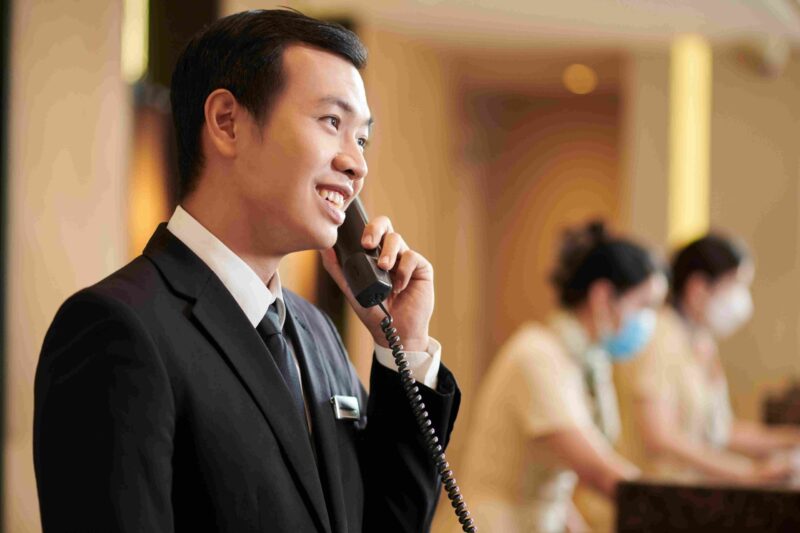 Hotel staff member in a suit speaking on the phone at a reception desk