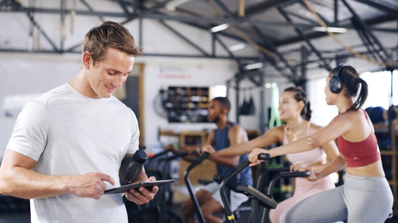 Gym technology helps a trainer manage a group cycling class with a tablet
