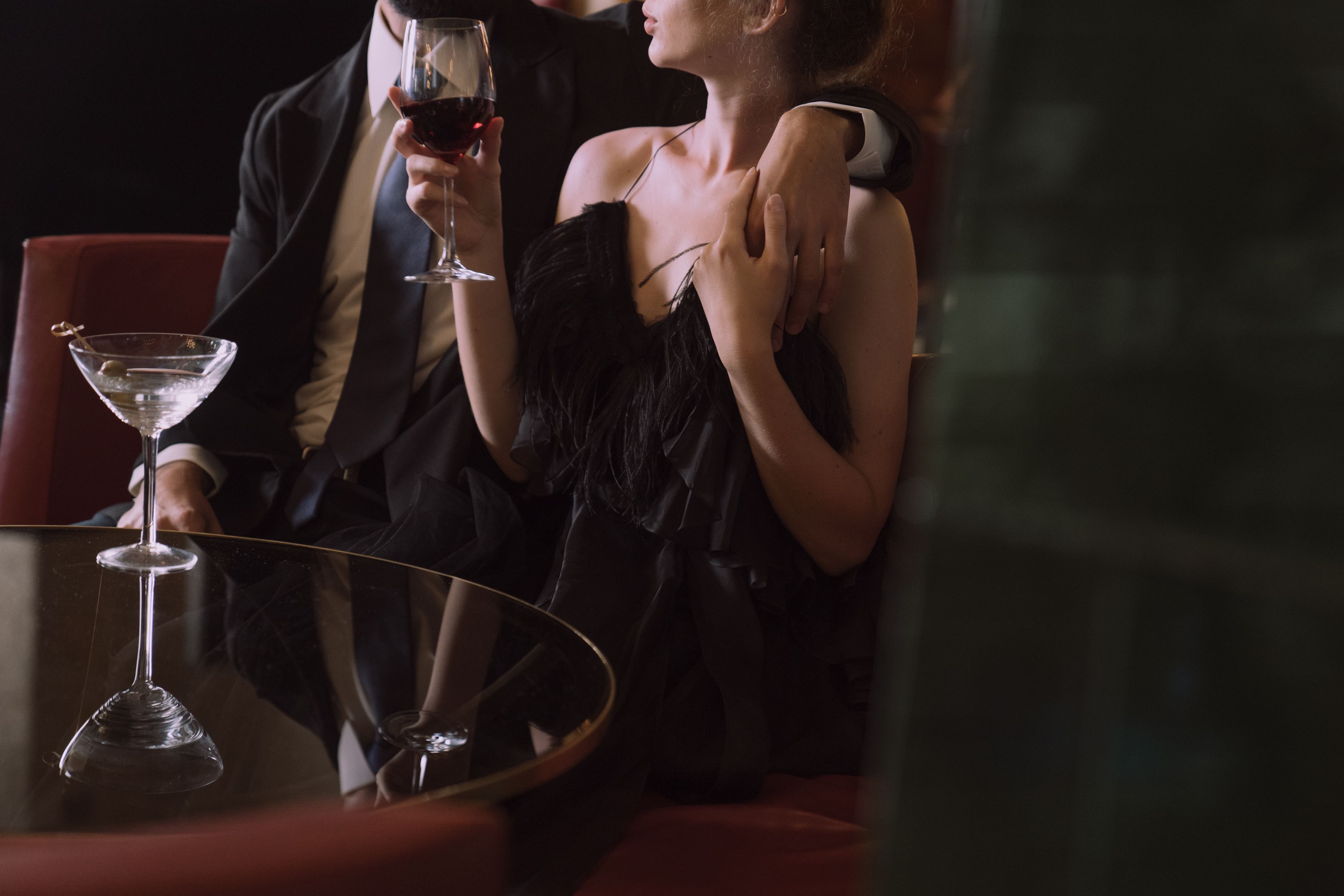 Elegantly dressed couple enjoying red wine at a stylish upscale restaurant