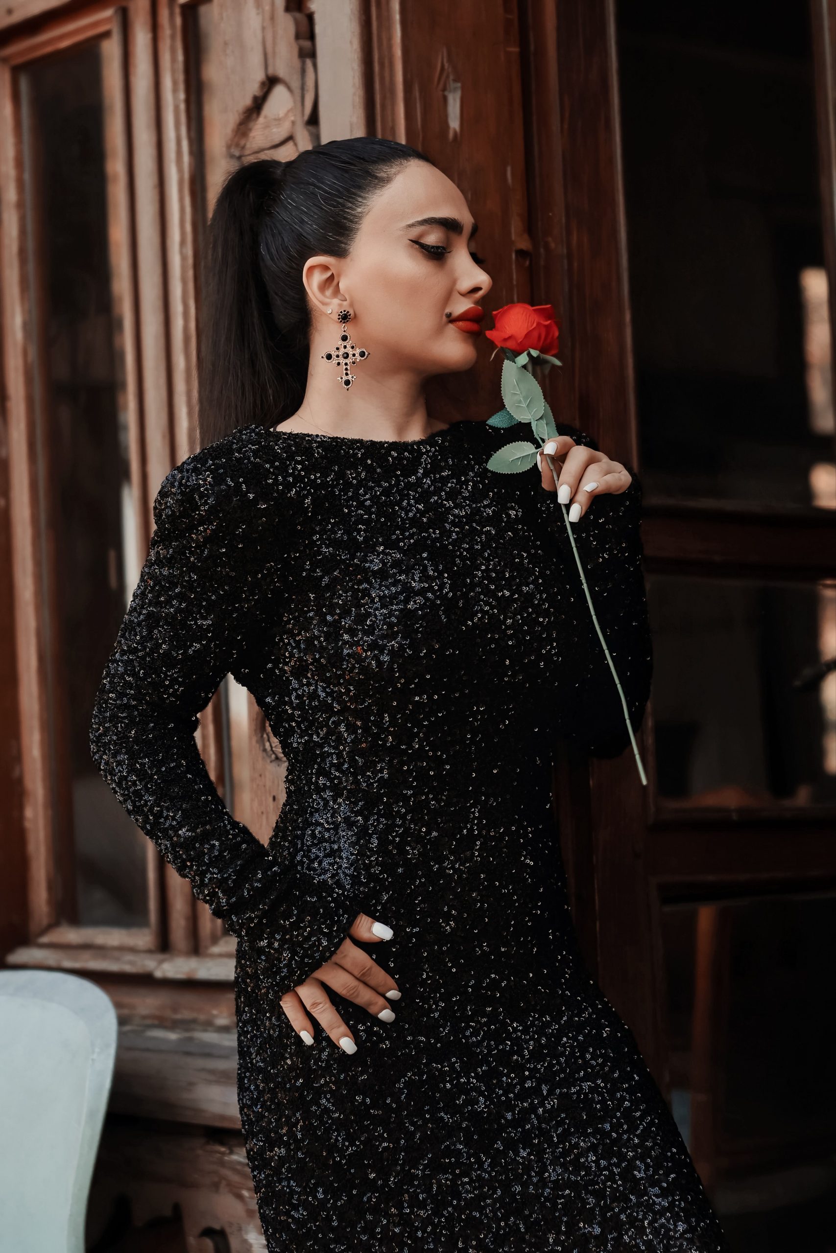 Elegant woman in a black sequined dress holding a red rose, exuding class and romance