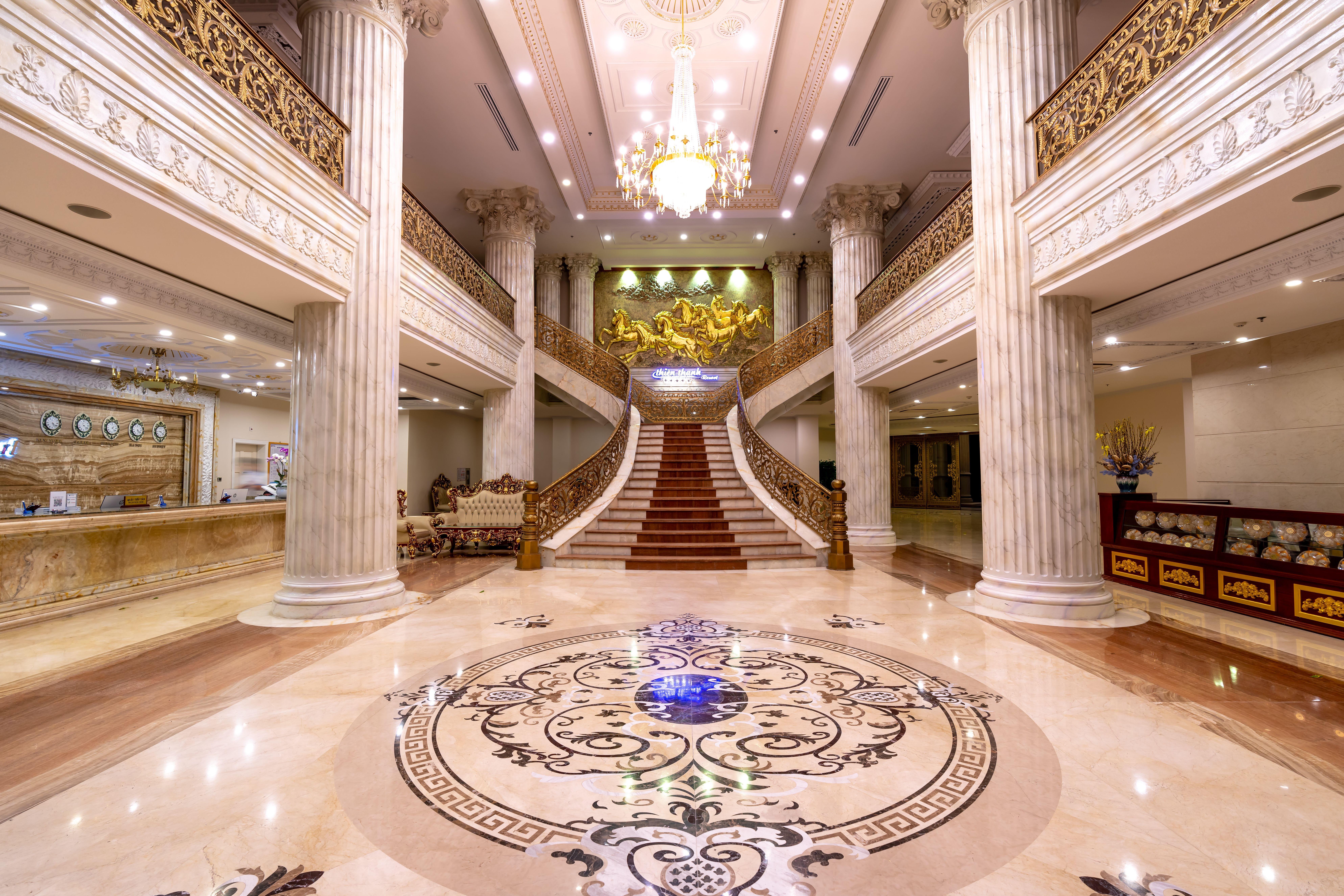 Elegant hotel foyer with grand staircase, marble floors and a dazzling chandelier