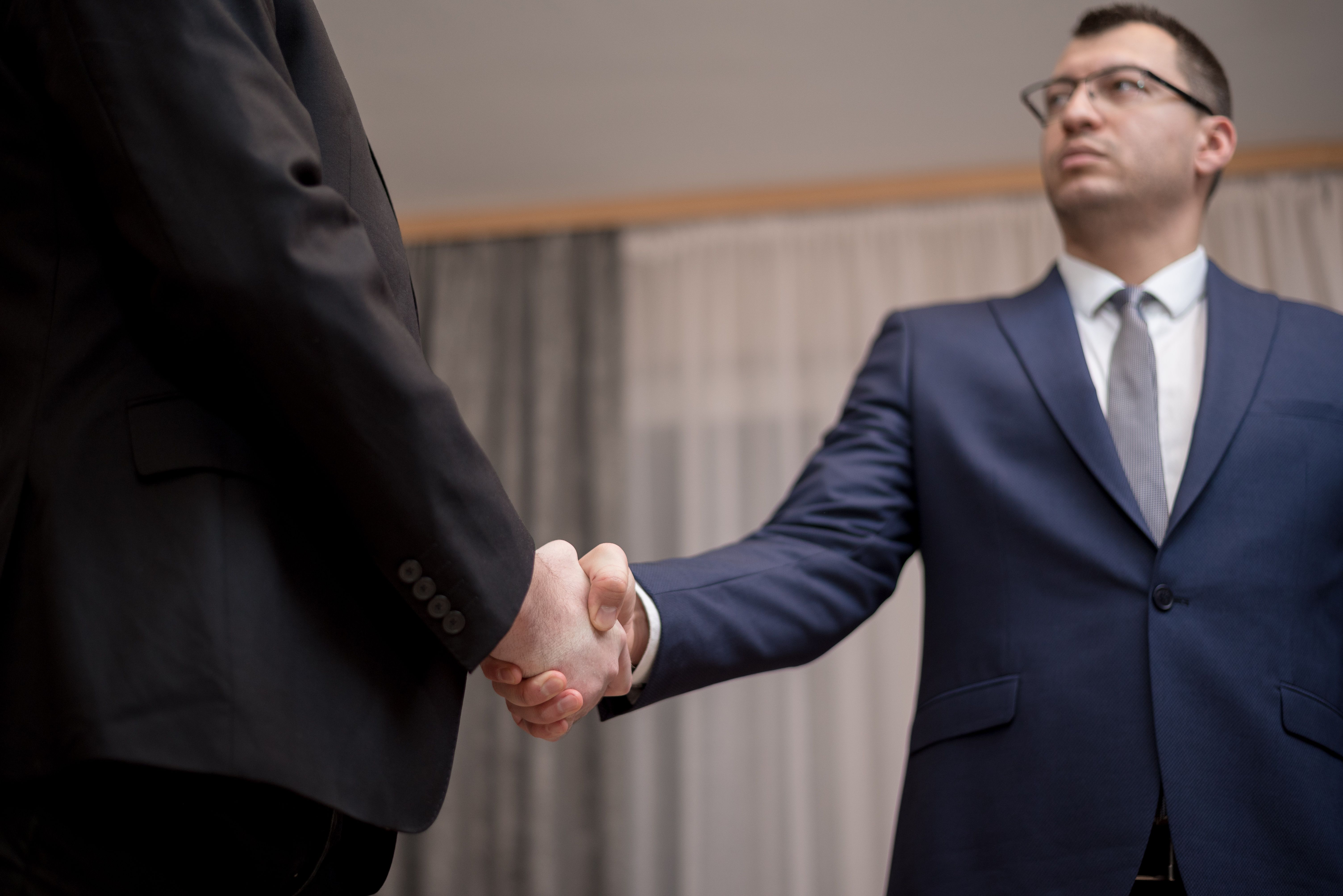 Two businessmen in formal attire shaking hands during a professional meeting
