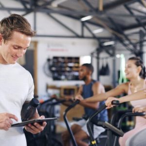Gym technology helps a trainer manage a group cycling class with a tablet