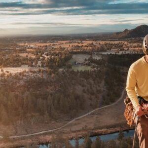 A climber prepares on a cliff above a river in Oregon, capturing the spirit of outdoor adventures for thrill-seekers